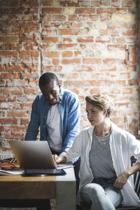 Male and female colleagues using laptop in office