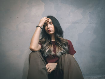 Portrait of young woman standing against wall