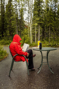 Man sitting on chair over road in forest