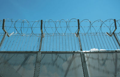 Metal fence against clouds and blue sky.