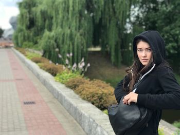 Young woman standing against trees