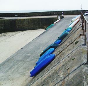 Blue deck chairs on beach against sky