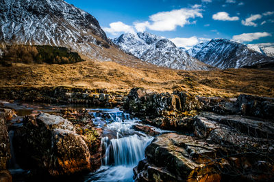 Scenic view of waterfall against mountains during winter