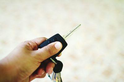 Cropped hand holding car key outdoors