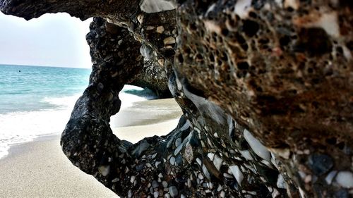 Close-up of rock formation at beach against sky