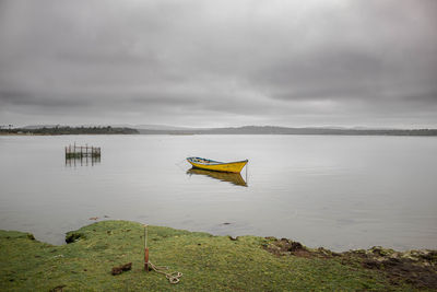 Boat moored on lake against sky