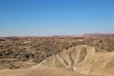 Scenic view of desert against clear blue sky