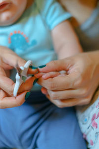 Cropped hands of mother cutting son nails