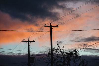 Low angle view of silhouette electricity pylon against sky during sunset