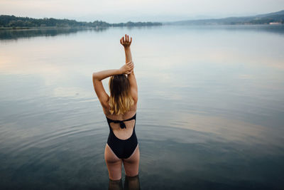 Young woman standing in river against sky