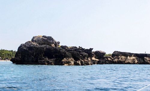 Rock formations in sea against clear sky