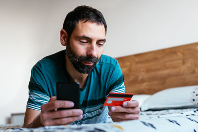 Man shopping online on a laptop lying on the bed at home