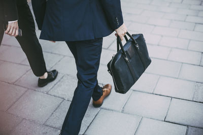 Low section of business colleagues walking on sidewalk