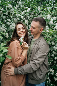 Young couple in love girl and man hugging blooming apple tree aroma of flowers outdoors