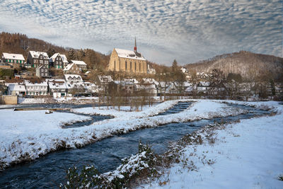 View of buildings by river in city during winter