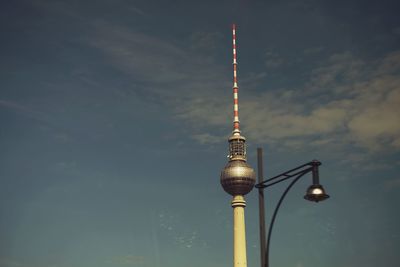 Low angle view of fernsehturm and street light against sky