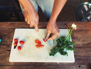 Midsection of woman chopping tomatoes on cutting board at table