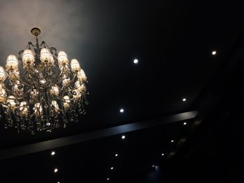 Low angle view of illuminated light bulb hanging from ceiling