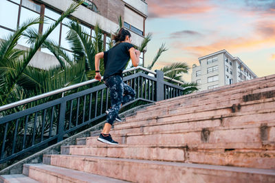 Female runner training up stairs over in urban runway on sunset