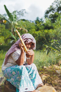 Dusun ethnic grandma , sabah, plays traditional bamboo musical instruments 