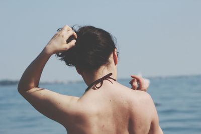 Rear view of shirtless woman in sea against sky