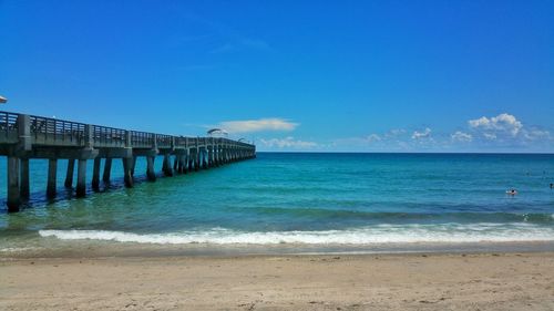 Scenic view of long pier in sea against clear blue sky