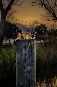 Wooden posts on field against sky at sunset
