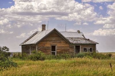 Abandoned house on field against sky