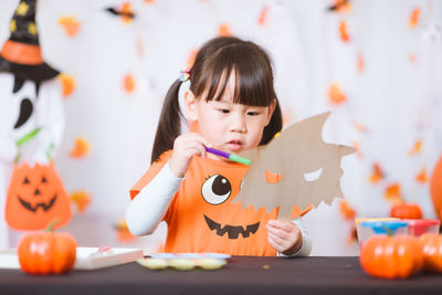 Young girl painting witch mask for halloween party at home