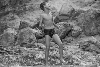 Full length of shirtless young woman on beach