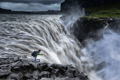 Scenic view of waterfall against rainbow in sky