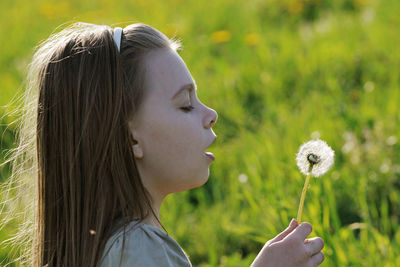 Close-up of cute girl blowing dandelion