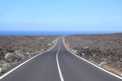 Empty road along landscape against sky