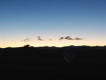 Scenic view of silhouette mountains against clear sky during sunset