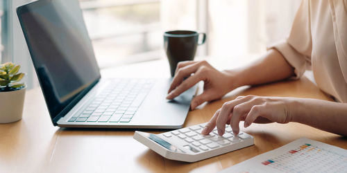 Midsection of man using laptop on table