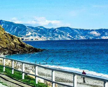 Scenic view of sea and mountains against blue sky