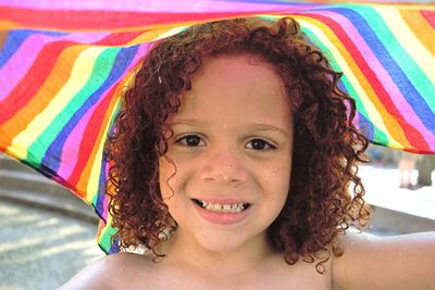 Portrait of smiling boy with wet curly hair and colorful textile