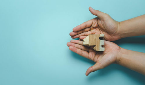 Close-up of hand holding blue over white background