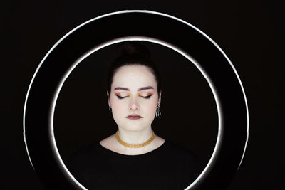 Portrait of a young woman over black background