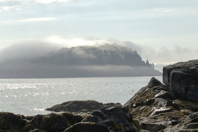 A view from the bar harbor shore of one of the porcupine islands covered in the morning fog in maine