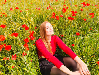 Beautiful young woman by poppy flowers on field