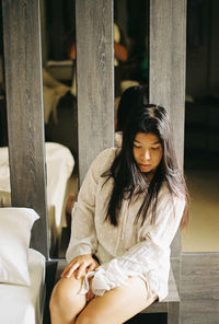 Young woman looking down while sitting outdoors