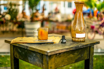 Close-up of dirty bottle and mug with papers on table