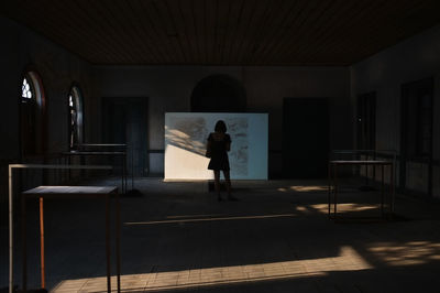 Rear view of silhouette woman standing in building