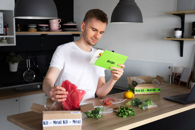 Caucasian white man unpack online home food delivery. box. services. dinner set from restaurant.