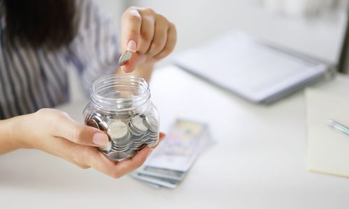 Midsection of woman holding glass jar on table