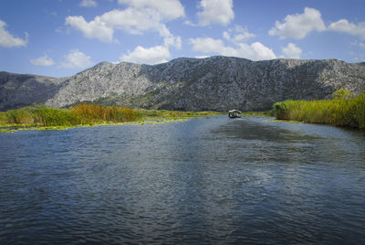 Scenic view of lake by mountain against sky