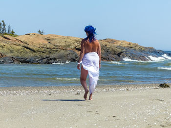 Rear view of woman on beach against clear sky