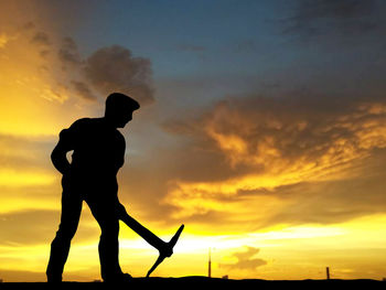 Silhouette man standing against orange sky during sunset