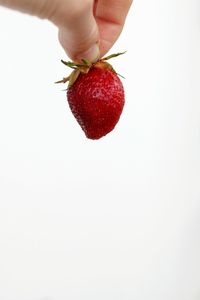 Studio shot of hand holding strawberry